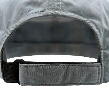 Photo of a fabric strap with an elastic connection to the back vent, and a plastic d-ring on the back of a cap